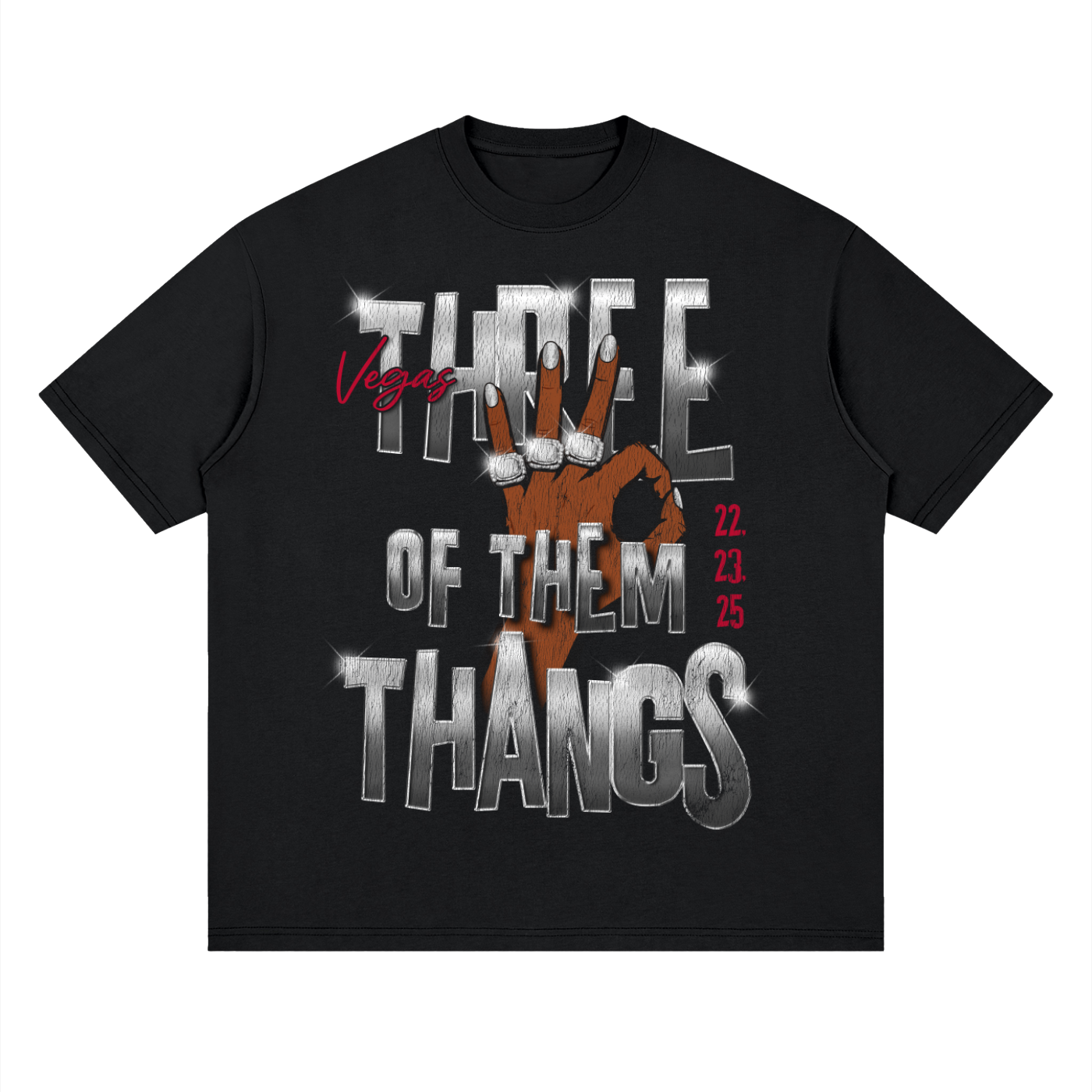 A black short-sleeve t-shirt with a graphic print on the front. The design features the text 'THREE OF THEM THANGS' in a metallic silver 3D font, a brown hand making a peace sign over the center, 'Vegas' in red script, and the numbers '22, 23, 25' in red on the right side.